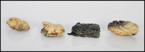 A group of four 20th Century Chinese carved toggles to include a green stone fu dog, a frog having