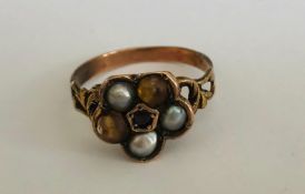 A 19th Georgian gold flower head ring having a central red stone with with three half pearls, having