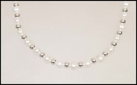 A row of cultured pearls having silver ball spacers and a silver stamped 925 lobster clasp. Length