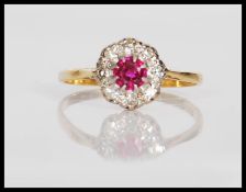 A hallmarked 18ct gold ring prong set with a round cut ruby having a halo of diamonds. Ruby approx