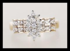 A hallmarked 9ct gold ring having a cluster of white stones to head with stepped shoulders set