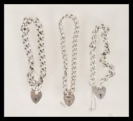 A group of three silver heart lock bracelets with curb link chains. One being stamped silver (