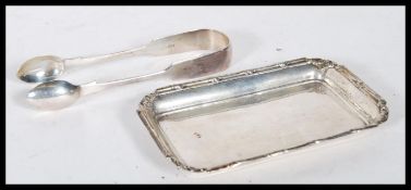 A silver hallmarked card tray and silver pair of tongues. The card/ pin tray having scroll and