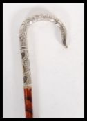 A silver white metal topped walking stick cane, having decorative crook handle with floral and
