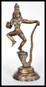 A cast brass Indian figurine of the Hindu God Lord Krishna dancing on the head of Kaliya, King of