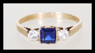 A hallmarked 9ct gold ladies ring set with a square cut blue stone flanked by two round cut white