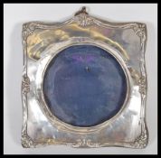 An early 20th Century silver hallmarked photo frame of square from having scrolled decoration
