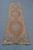 A large early 20th century handwoven Persian - Islamic runner rug having ochre faded red ground with