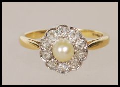 A hallmarked 18ct gold dress ring being set with a central pearl to the head and a halo of old cut