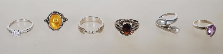 A group of six silver rings to include a stamped 925 set with an amber type cabochon in a decorative