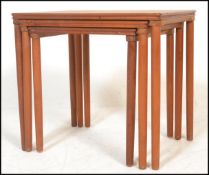 A retro 20th Century teak wood Danish nest of three graduating occasional tables raised on  turned