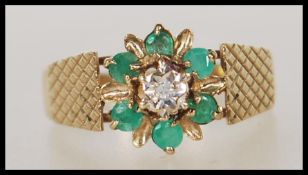 A hallmarked 9ct gold cluster ring having a central illusion set diamond with a halo of emeralds