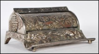 A silver plated desk inkwell having a domed rotating lid with quill holder to the front having