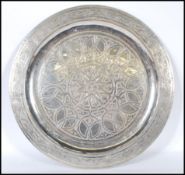 An early 20th Century Anglo Persian silver white metal wall charger having a chase design border