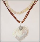 A beaded opalescent necklace having a yellow metal spring clasp along with a carved opalescent stone