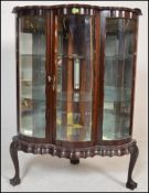 A 20th Century mahogany glazed corner display cabinet, the serpentine fronted cabinet having a