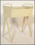 A vintage retro wooden sewing box being painted in white with angular tapering legs and brass