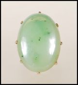A ladies 9ct gold dress ring set with a large oval green nephrite cabochon. Unmarked but tests as