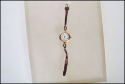 A early 20th Century hallmarked 9ct gold ladies wrist watch having a white enamel face with gilt