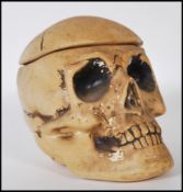 A 20th Century novelty chalk ware tobacco jar in the form of a skull, the lid being the coronal
