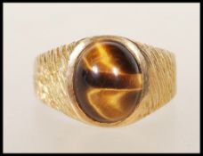 A stamped 9ct gold vintage 1970's ring set with an oval tigers eye cabochon to the head having