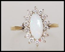A hallmarked 9ct gold ring set with an oval cut opal with a halo of white stones. Marked with import
