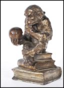 A Darwinian style cast metal novelty table cigarette / cigar lighter, in the form of a seated monkey