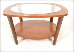 A 20th Century retro teak wood circular coffee table with drop in glass centre raised on shaped