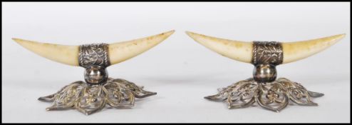 A pair of silver hallmarked and bon knife rests, the bone carved in the form of horns raised on