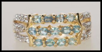 A hallmarked 9ct gold dress ring having three bands set with white and green accent stones.