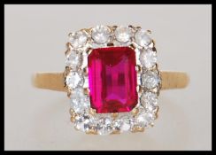 A hallmarked 9ct gold ladies dress ring set with a square cut red stone and a halo of white