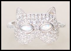 A silver CZ and opalite ladies dress ring in the form of a cats head being set to a plain shank.