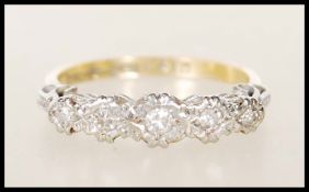 A stamped 18ct gold and platinum ring having five graduated round cut diamonds within an illusion