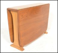 An Ercol beech and elm wood light drop leaf sutherland occasional - coffee table being raised on