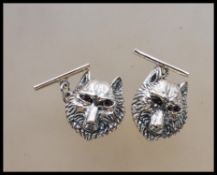 A pair of silver wolf mask gents cufflinks. Each with wolf head design having chain backs. Verso