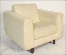 A retro cream leather armchair by Habitat raised on saquer wooden supports. Measures 82cms x 94cms x