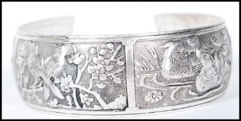A 20th Century Chinese silver bangle bracelet having decorative repousse panels depicting birds
