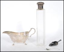 A silver hallmarked sauce boat being raised on cab feet with a shaped scrolled handle with an