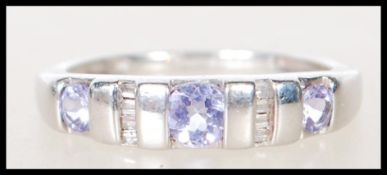 A stamped 375 9ct white gold ring channel set with three purple stones having baguette diamond