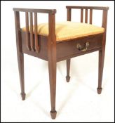 An early 20th Century Edwardian mahogany piano stool with upholstered lifting top, scroll arms and