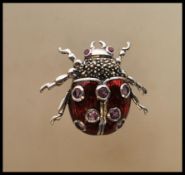 A silver and enamel bug brooch. The brooch in the form of a ladybird with red body and inset