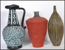 A group of three 20th Century studio pottery vases and a jug. One vase of tapering form having red