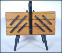 A vintage retro 20th Century wooden cantilever sewing box having metamorphic action raised on shaped