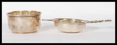 A silver hallmarked tea strainer and bowl combination. Pierced bowl with shaped handles.