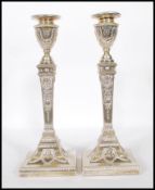 A pair of  late Victorian silver hallmarked large filled candlesticks having square terraced bases