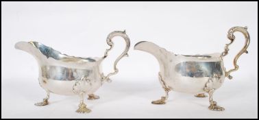 A pair of large late Victorian silver hallmarked gravy boats being raised on pad hairy paw feet.