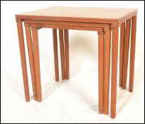 A retro 20th Century Danish teak wood nest of three graduating occasional tables raised on shaped