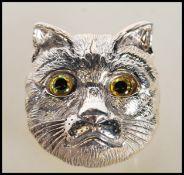 An unusual ladies silver brooch in the form of a cats head with glass eyes. Pin verso. Measures 3cms