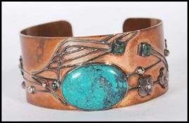 An early 20th Century Arts and Crafts bangle bracelet having a copper body with applied silver