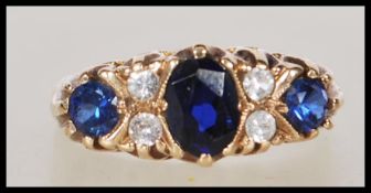 A hallmarked 9ct gold ladies ring set with three blue stones to the head with white accent stones.